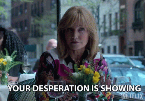 A Woman Sitting At A Table With Flowers And Wine Glasses Says " Your Desperation Is Showing " GIF
