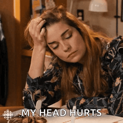 A Woman Sitting At A Table With Her Hand On Her Head And The Words My Head Hurts GIF
