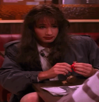A Woman Sitting At A Table With Red Nails GIF