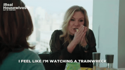 A Woman Sitting At A Table With The Words I Feel Like I 'M Watching A Trainwreck GIF
