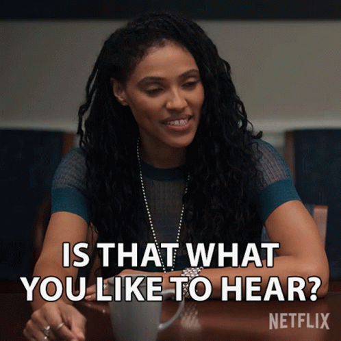 A Woman Sitting At A Table With The Words " Is That What You Like To Hear " Written Above Her GIF