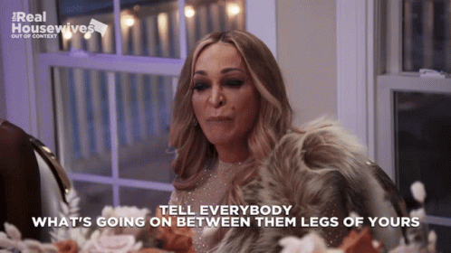 A Woman Sitting At A Table With The Words Tell Everybody What 'S Going On Between Them Legs Of Yours On The Bottom GIF