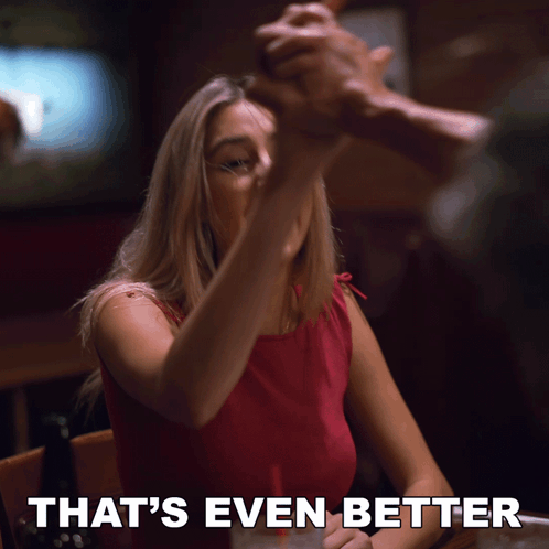 A Woman Sitting At A Table With The Words That 'S Even Better Written Below Her GIF