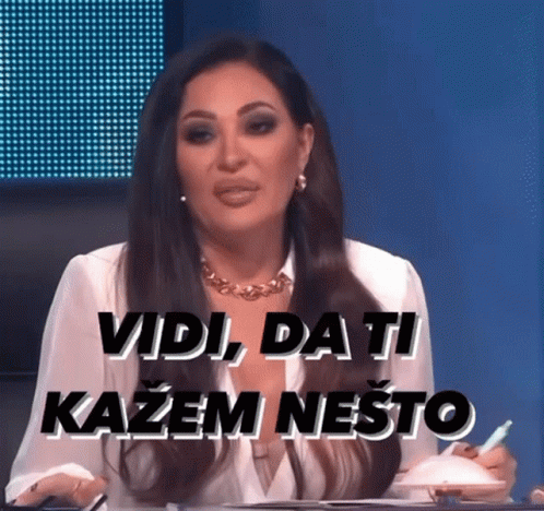 A Woman Sitting At A Table With The Words Vidi Da Ti Kazem Nešto Written On The Screen Behind Her GIF