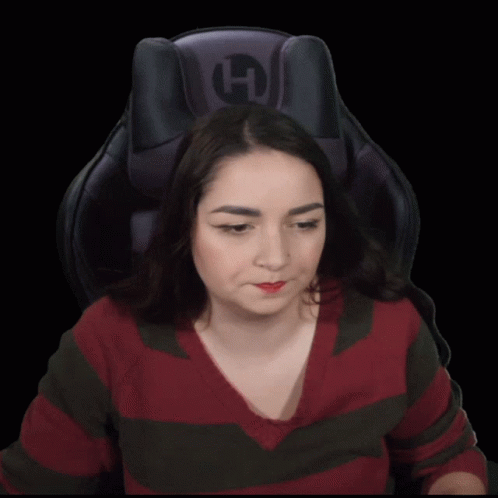 a woman sitting in a chair drinking from a can with a straw and the letter h on the back