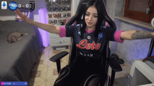 A Woman Sitting In A Chair Wearing A Jersey That Says Lete GIF