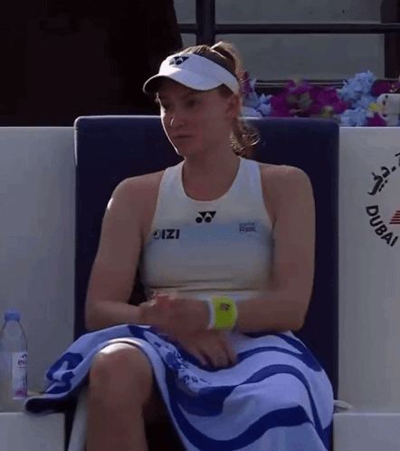 A Woman Sitting In A Chair With A Towel Around Her Waist That Says Dubai On It GIF