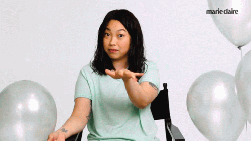 A Woman Sitting In A Chair With Balloons And Marie Claire On The Bottom Right GIF