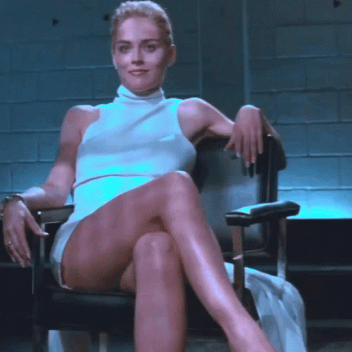 A Woman Sitting In A Chair With Her Legs Crossed GIF