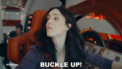 A Woman Sitting In A Chair With The Words Buckle Up Above Her GIF