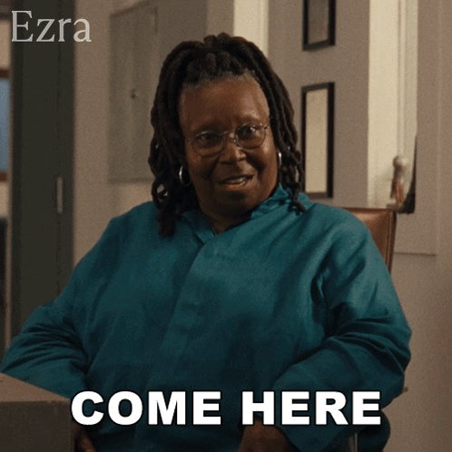 A Woman Sitting In A Chair With The Words Come Here Behind Her GIF