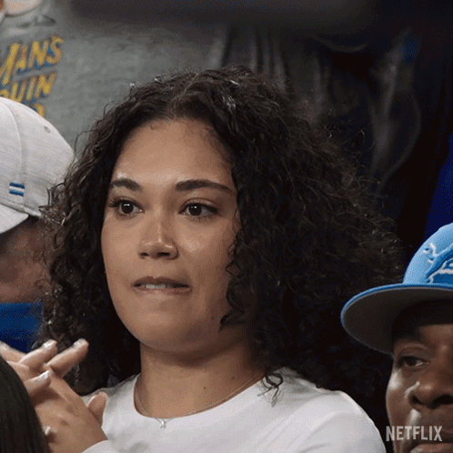 A Woman Sitting In A Crowd With A Netflix Logo On The Bottom Left GIF