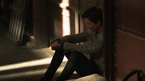 A Woman Sitting In A Doorway With A Shadow On The Wall GIF
