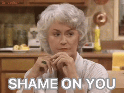 A Woman Sitting In A Kitchen With The Words " Shame On You " Written On Her Face GIF