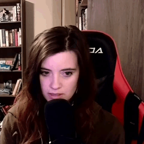 A Woman Sitting In A Red Chair With The Letter A On The Back GIF