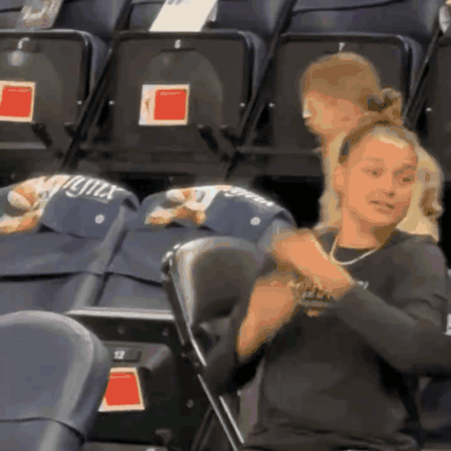 A Woman Sitting In A Stadium With A Hat That Says Lynx GIF
