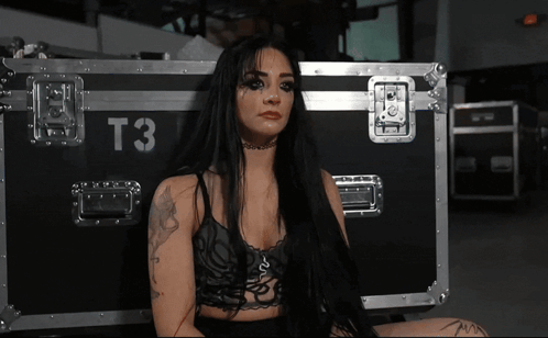 A Woman Sitting In Front Of A Case That Says T3 On It GIF