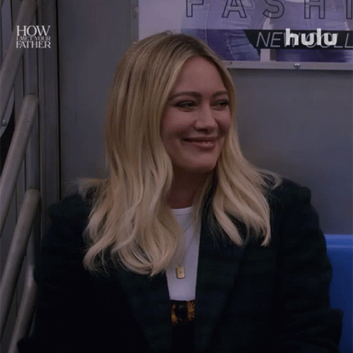 A Woman Sitting In Front Of A Sign That Says How I Met Your Father GIF