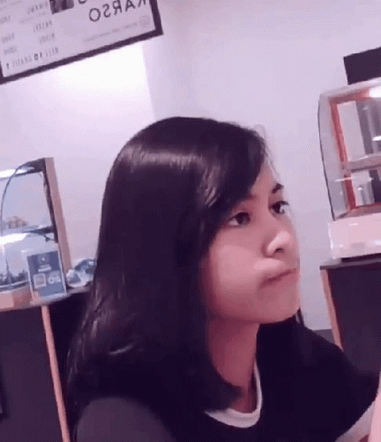A Woman Sitting In Front Of A Sign That Says ' O2aa ' On It GIF