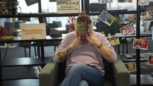 A Woman Sitting In Front Of A Sign That Says Type One On It GIF