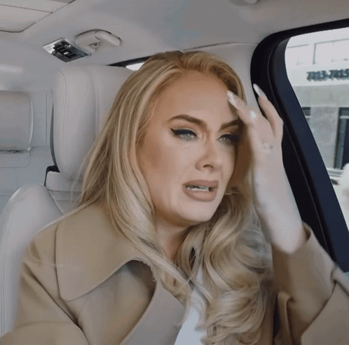 A Woman Sitting In The Back Seat Of A Car With Her Hand On Her Head GIF