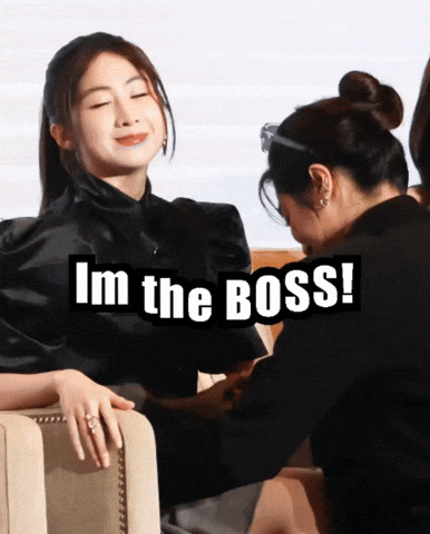A Woman Sitting Next To Another Woman With The Words I 'M The Boss Below Her GIF