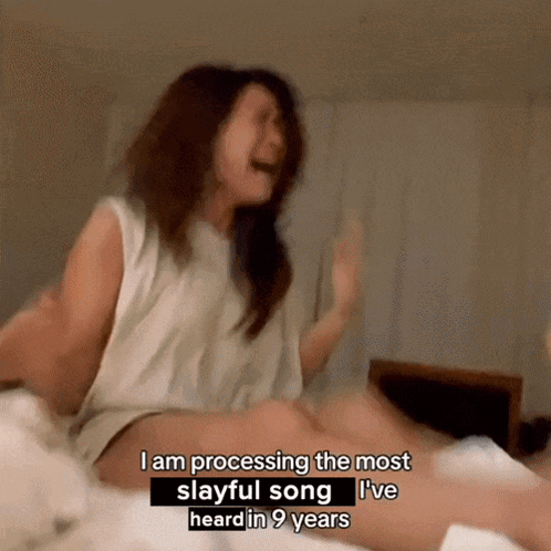 A Woman Sitting On A Bed Says I Am Processing The Most Slayful Song I 'Ve Heard In Nine Years GIF