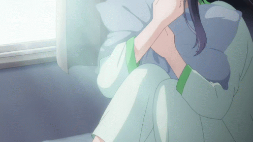 A Woman Sitting On A Bed With A Pillow In Her Lap GIF