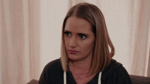 A Woman Sitting On A Couch Looking At The Camera GIF