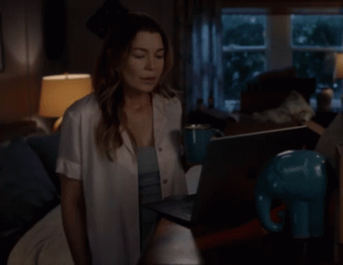 A Woman Sitting On A Couch Using A Laptop GIF
