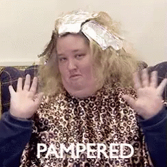 A Woman Sitting On A Couch With Pampered Written On The Bottom Of Her Face GIF