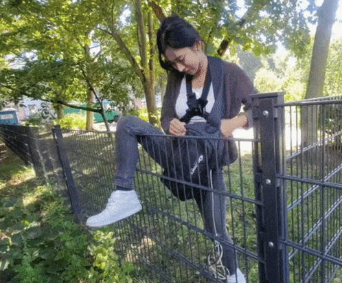 A Woman Sitting On A Fence With A Bag That Says Reebok GIF