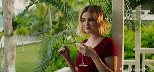 A Woman Sitting On A Porch Holding A Martini Glass GIF
