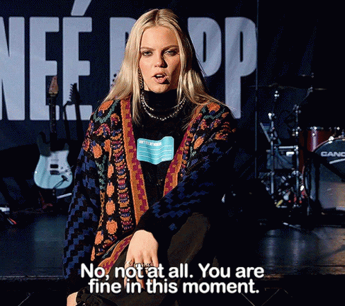 A Woman Sitting On A Stage With The Words " No Not At All You Are Fine In This Moment " Written Below Her GIF
