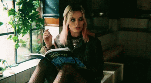 A Woman Sitting On A Window Sill Reading A Book Called A Level Biology GIF