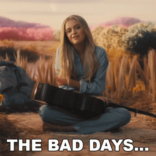 a woman sitting on the ground with a guitar and the words the bad days