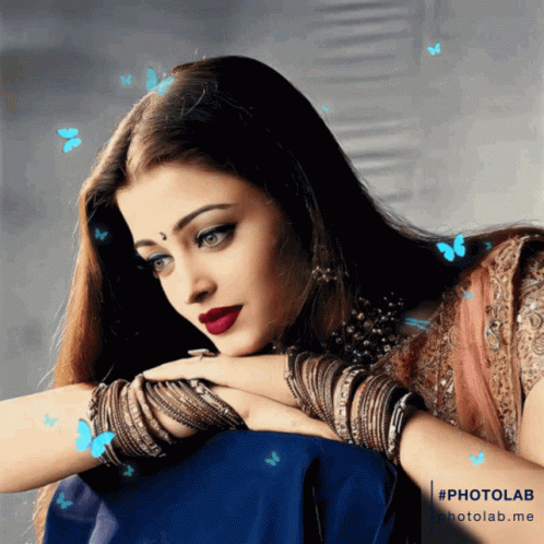 A Woman Sitting With Her Head Resting On Her Hand With Butterflies Flying Around Her Head GIF