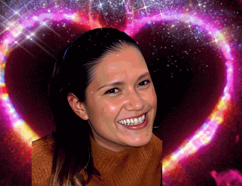 A Woman Smiles In Front Of A Heart Shaped Background GIF