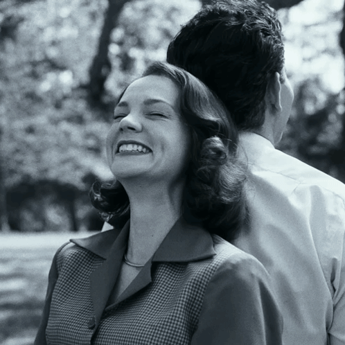 A Woman Smiles With Her Eyes Closed While A Man Holds Her Back GIF