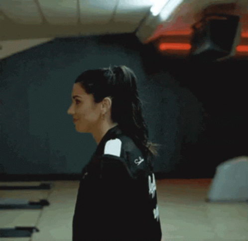 A Woman Smoking A Cigarette In A Room With A Man Standing Behind Her GIF