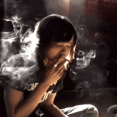 A Woman Smoking A Cigarette Wearing A Black Shirt That Says Escape GIF