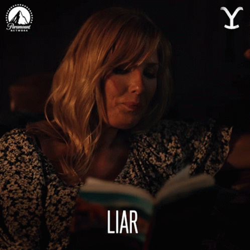 A Woman Smoking A Cigarette While Reading A Book Titled Liar GIF