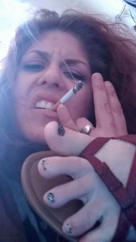 A Woman Smoking A Cigarette With A Ring On Her Left Hand GIF