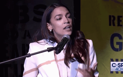A Woman Speaking Into A Microphone In Front Of A Sign That Says C-Sf 40Y GIF