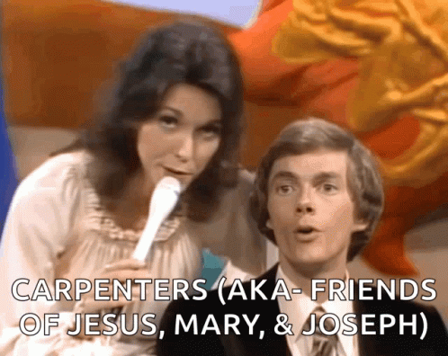 A Woman Speaking Into A Microphone Next To A Man With The Words Carpenters Aka Friends Of Jesus Mary & Joseph GIF