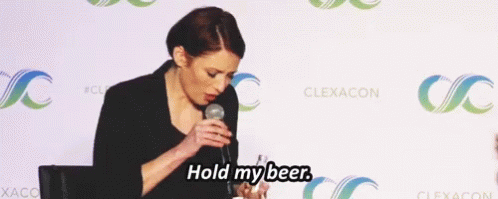 A Woman Speaking Into A Microphone With The Words Hold My Beer GIF