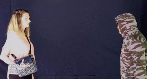 A Woman Spraying A Man With A Purse That Says Tracer Security On It GIF