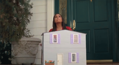 A Woman Standing In Front Of A Doll House GIF