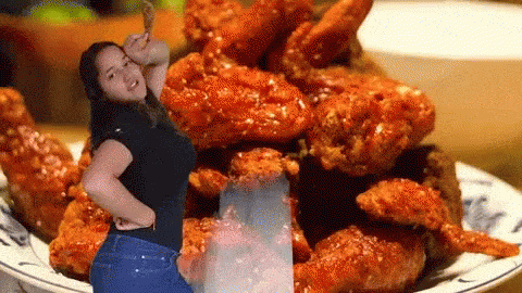 A Woman Standing In Front Of A Plate Of Fried Chicken Wings GIF