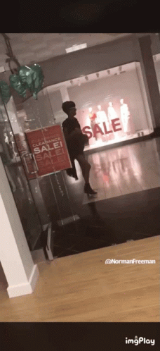 A Woman Standing In Front Of A Store With A Sign That Says Clearance Sale GIF